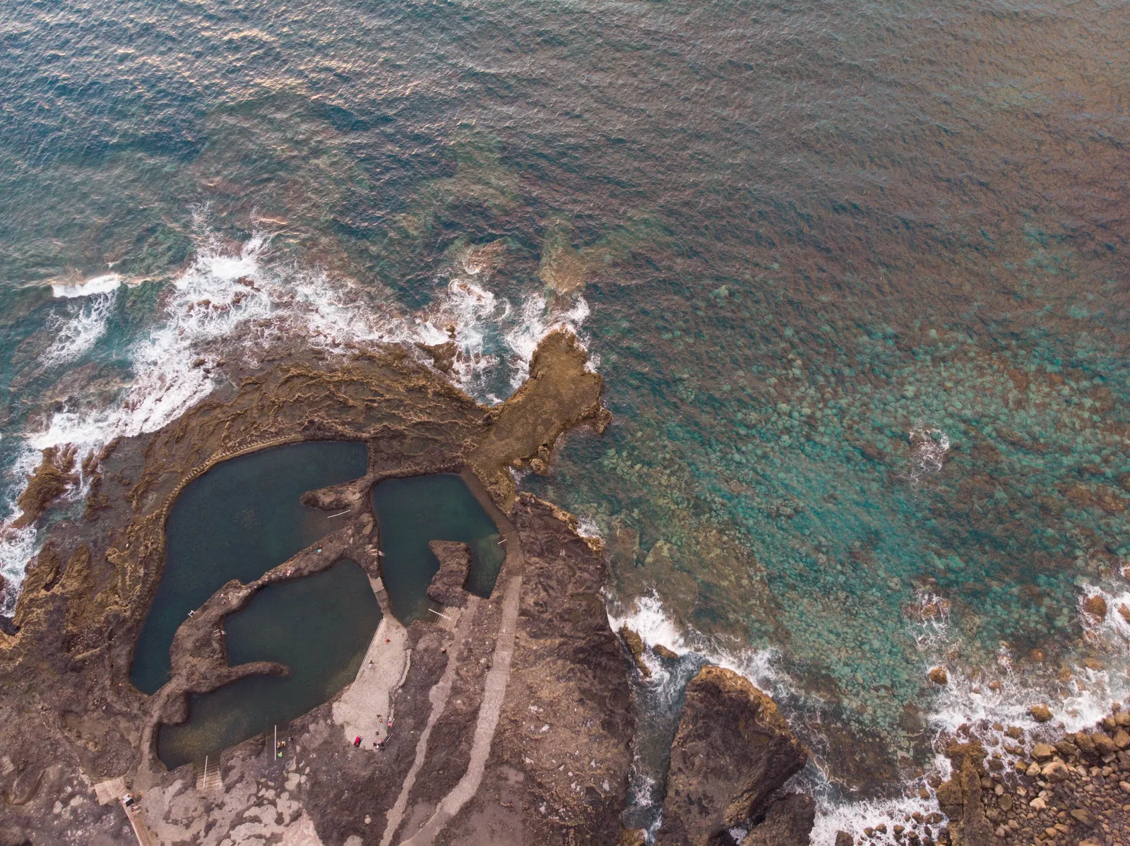 Rock pools on the shore seen from above, with waves breaking