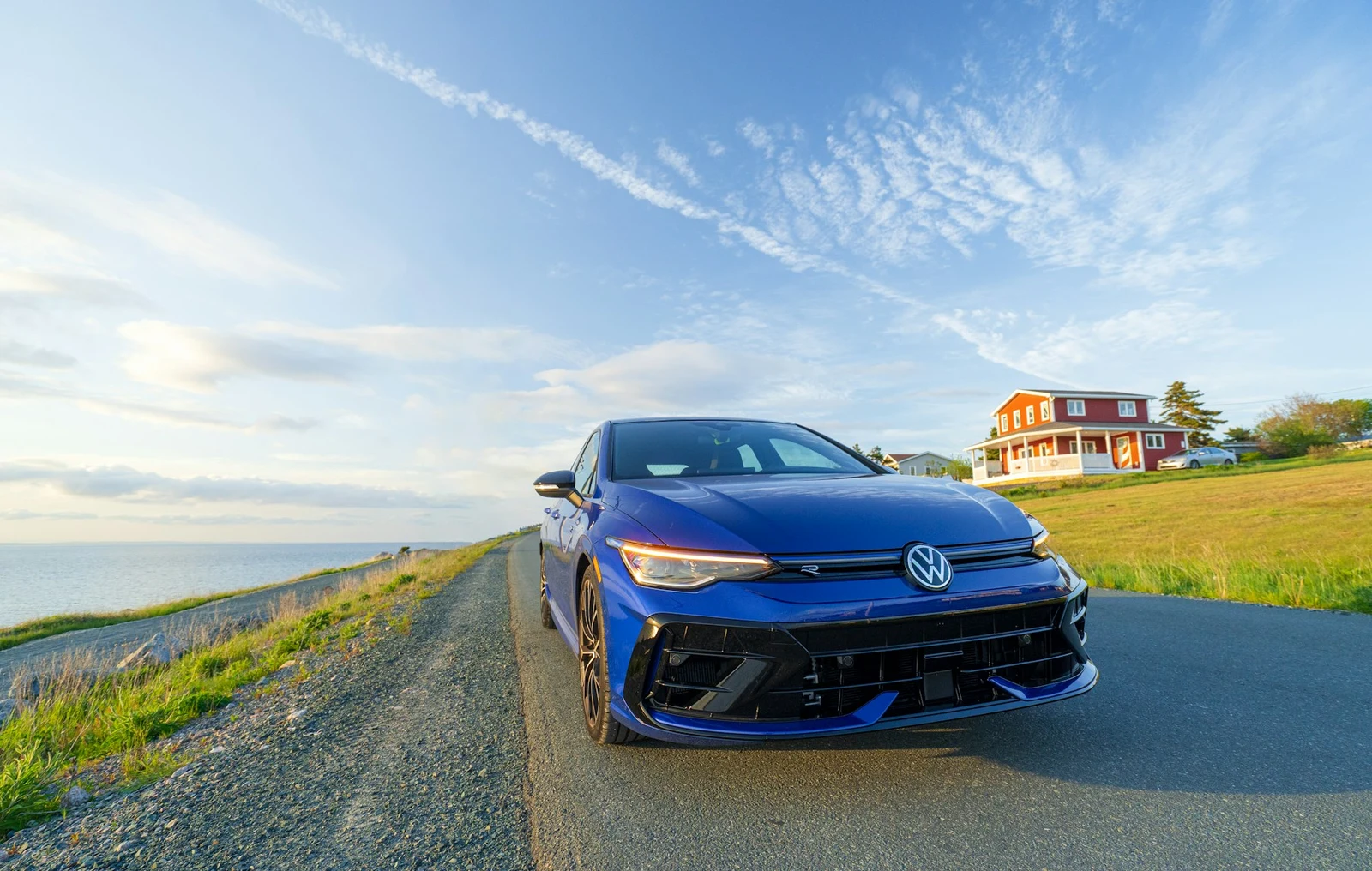 Une Volkswagen Golf bleue sur une route côtière, avec la mer en arrière-plan