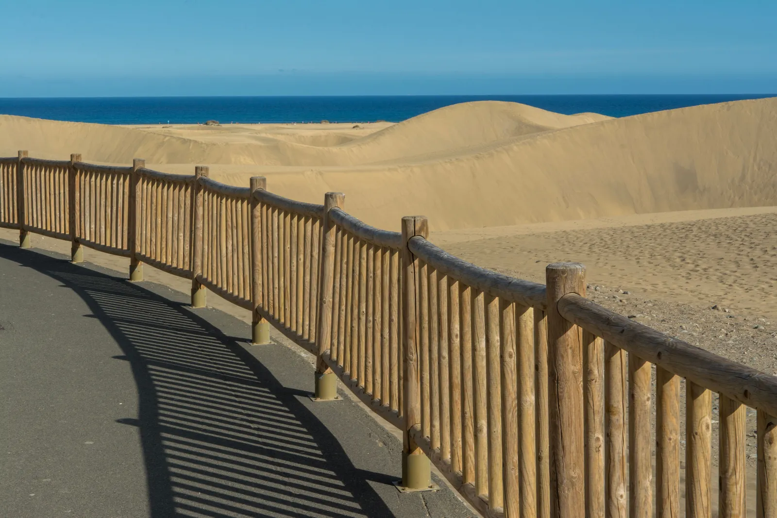 Une barrière en bois le long d'un chemin entre les dunes et la mer