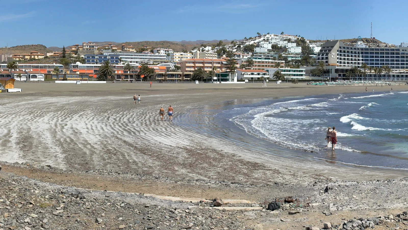 Une plage de sable bordée d'hôtels et d'appartements bas